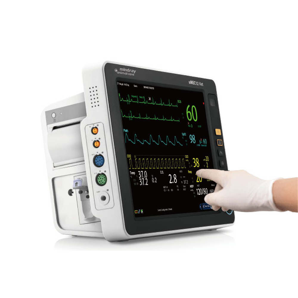 Gloved finger tapping the screen of a Mindray uMEC12 Vet patient monitor with waveforms and vital sign numbers displayed